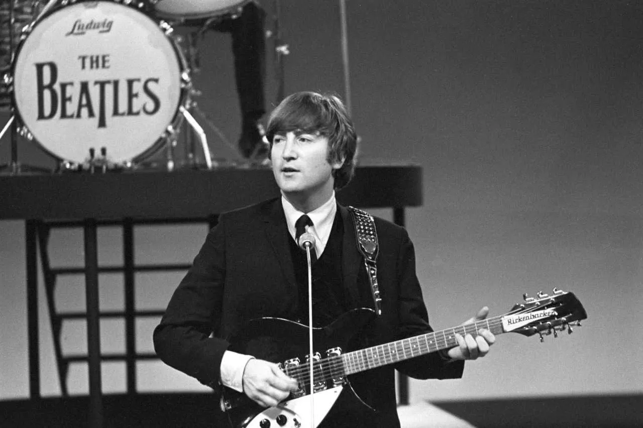 John Lennon playing his guitar during a Beatles concert