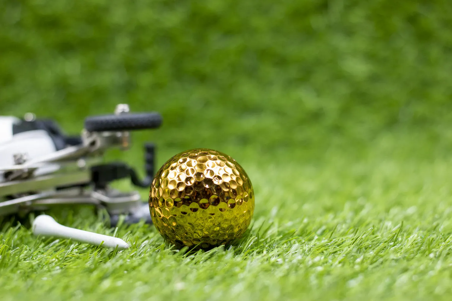 Golden golf ball is on green grass