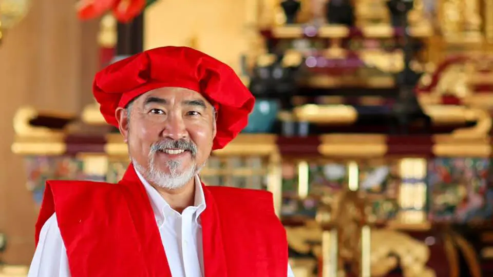 A Japanese elder donning the traditional red Kanreki attire amidst a festive setting