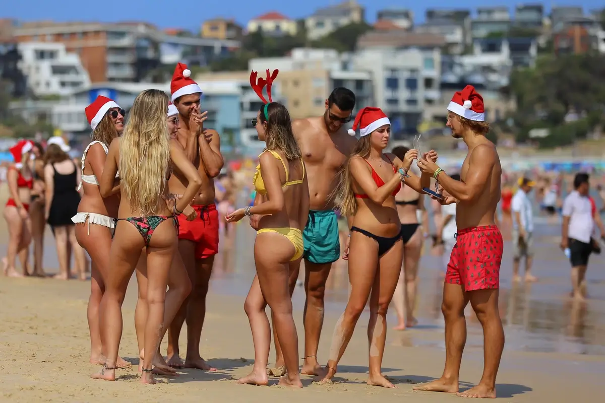 Crowded Australian beach with swimmers wearing Santa hats