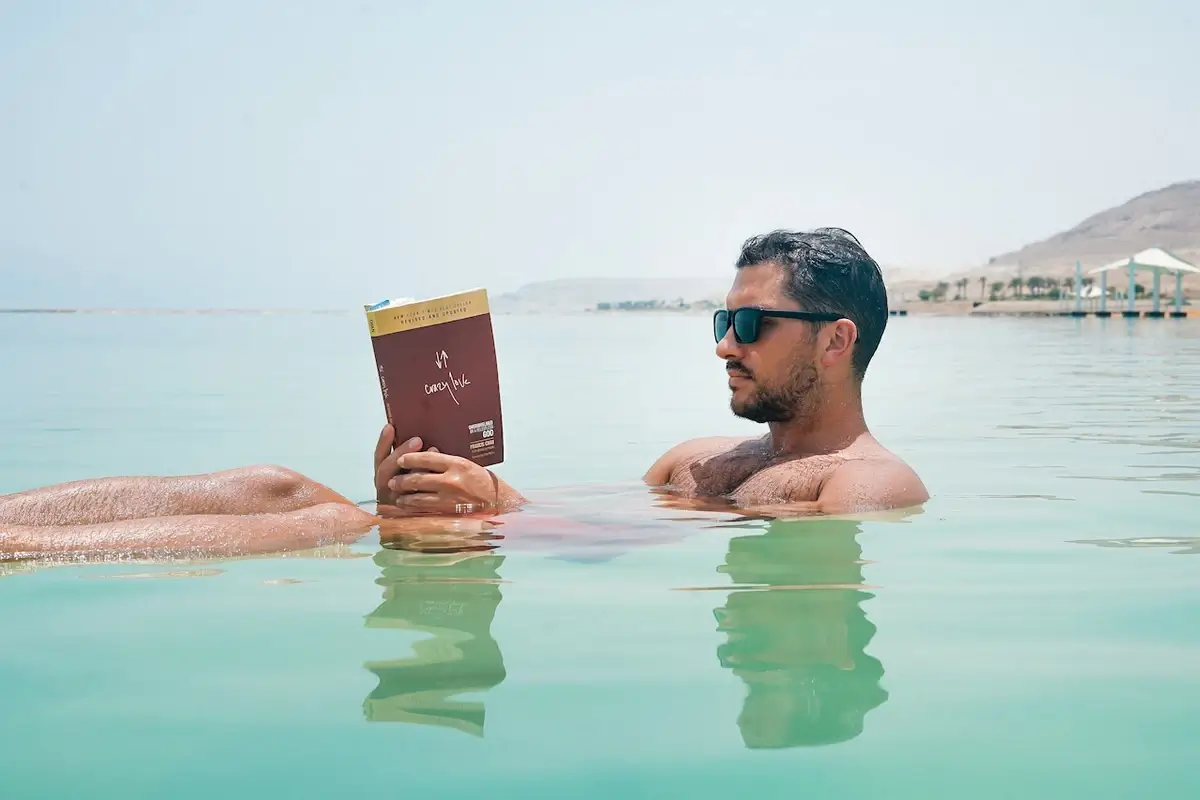 A tourist floating effortlessly in the Dead Sea, reading a book