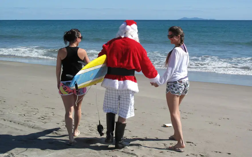 Santa on the beach in Australia with a surfboard under his arm