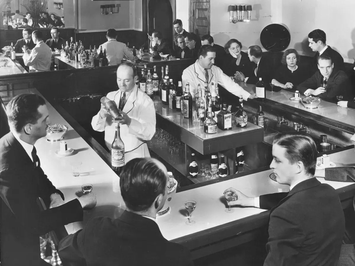 An antique photo of a 1920s speakeasy, complete with patrons savoring covert cocktails