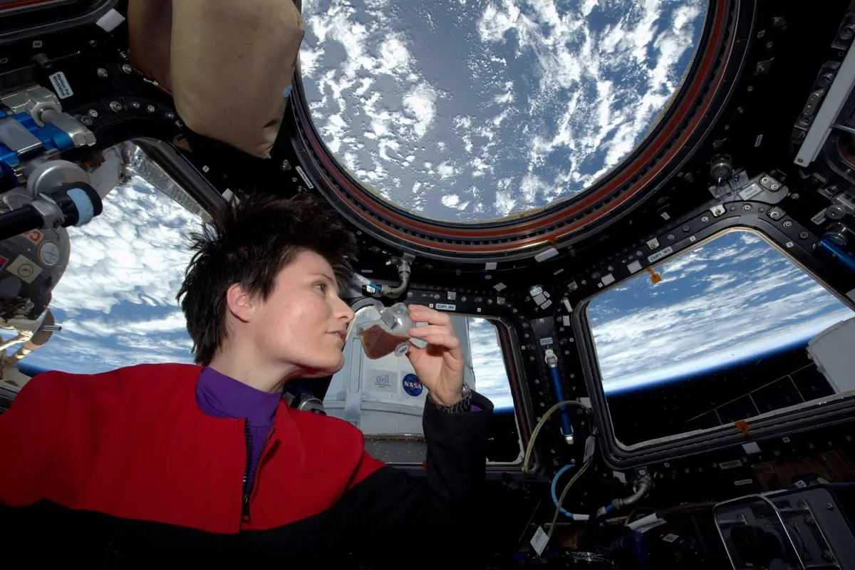 An astronaut using the "zero-g coffee cup" aboard the ISS