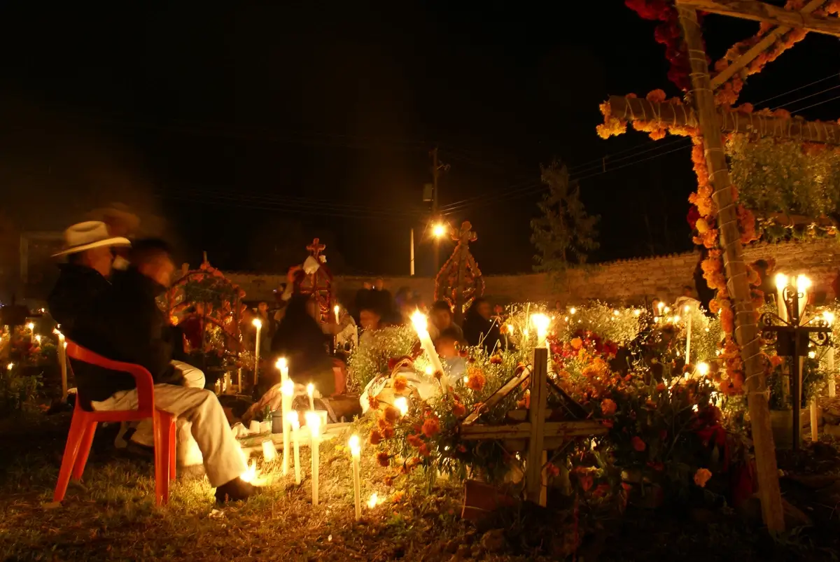 Day of the Dead: Families celebrating around lavishly decorated graves at night