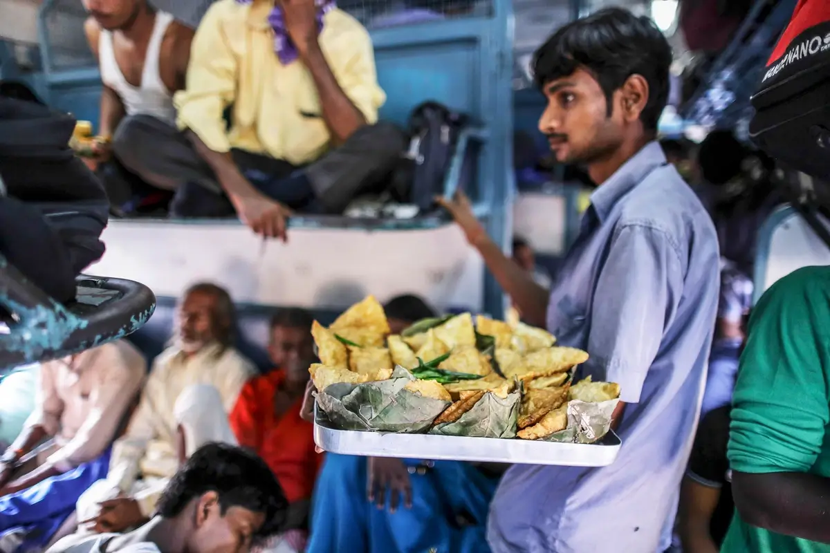 A vendor sells food on a train in India