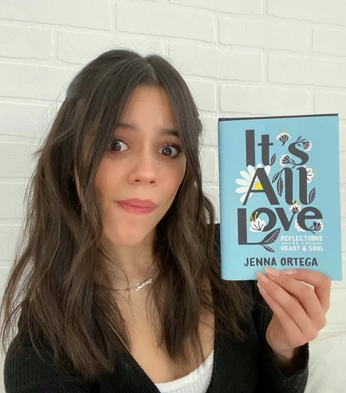 Jenna Ortega holding her book, "It's All Love."