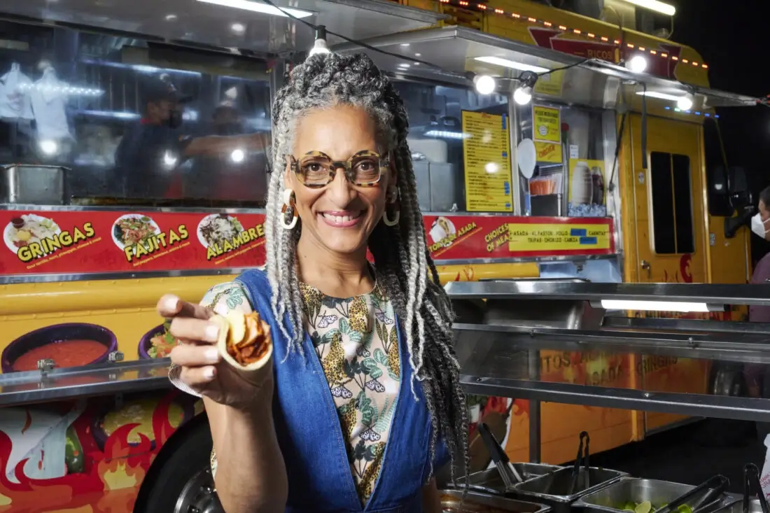 Carla Hall smiling in front of a food truck