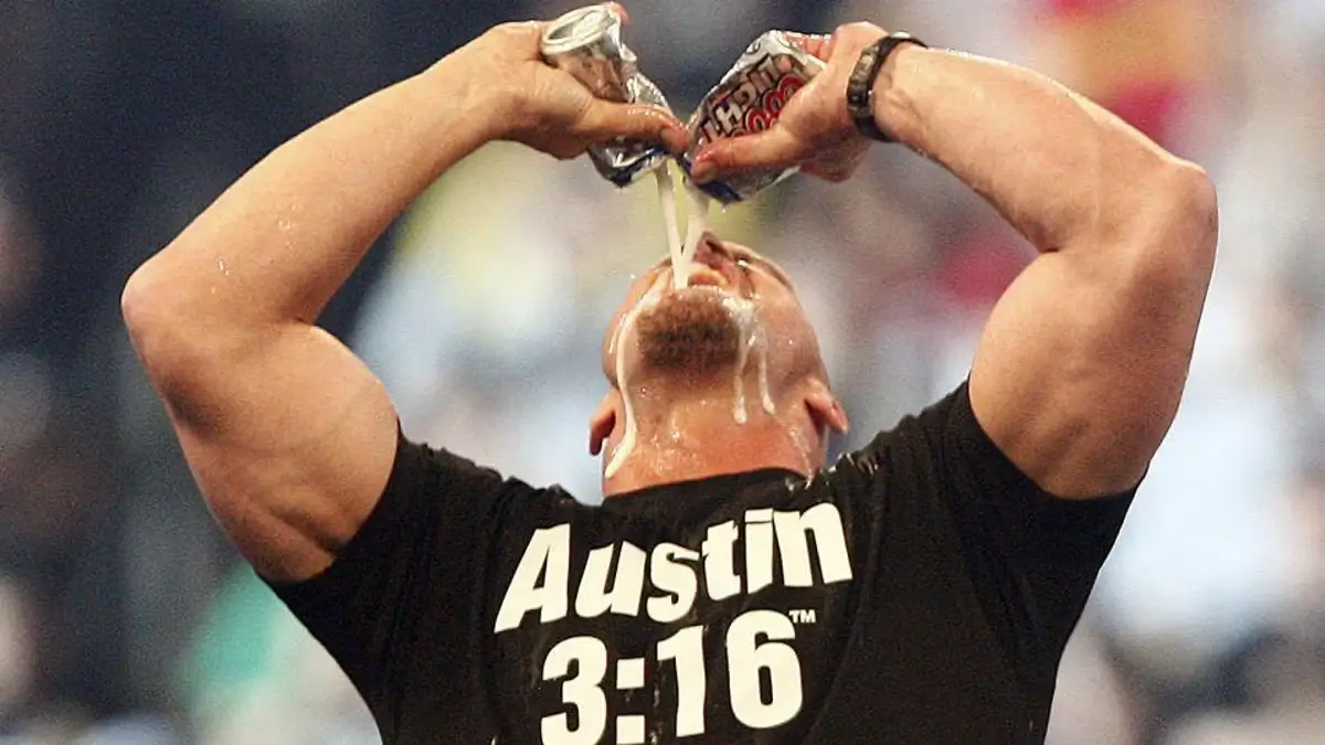 Steve Austin celebrating in the ring with a beer can in each hand
